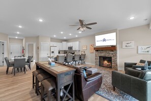 A modern living room with a fireplace, leather seating, a dining area, and a kitchen. - Lake Taneycomo Front Condo Minutes to Branson Landing_Shared Outdoor Pool_Free Attraction Tickets (Branson)