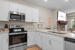 A modern kitchen with white cabinetry, stainless steel appliances, and a stone backsplash. - Lake Taneycomo Front Condo Minutes to Branson Landing_Shared Outdoor Pool_Free Attraction Tickets (Branson)
