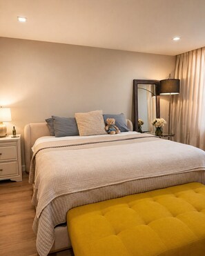 Ein Schlafzimmer mit Bett, Nachttischen, einer Lampe, einem Spiegel und einer Sitzbank.