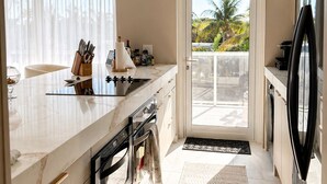 A modern kitchen with a marble countertop, stainless steel appliances, and a view to the outdoors. - 2-bedroom apartment in fantastic Fort Lauderdale beach walking distance (Fort Lauderdale)