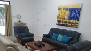 Ein Wohnzimmer mit einer Couch, Sesseln, einem Couchtisch und einem Gemälde an der Wand.