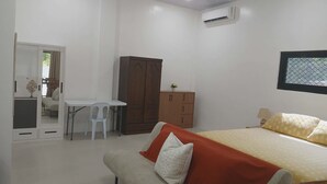 Ein Schlafzimmer mit einem Bett, einem Schreibtisch, einem Kleiderschrank und einer Klimaanlage.