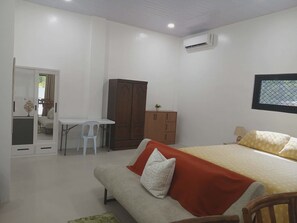 Quarto com cama, escrivaninha, guarda-roupa e ar condicionado.