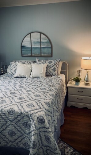 A bedroom with a bed, a nightstand, a lamp, and a wall-mounted window. - Charming 4-bedroom retreat near beautiful Lake Ouachita (Mount Ida)