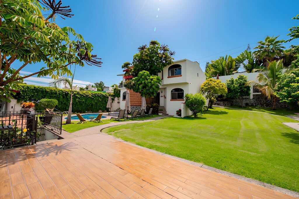 Una propiedad residencial con un césped cuidado, piscina y un patio con mobiliario exterior.