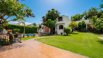 Una propiedad residencial con un césped cuidado, piscina y un patio con mobiliario exterior.