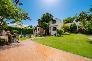 Una propietat residencial amb un jardí ben cuidat, piscina i zona de terrassa amb mobles d'exterior.