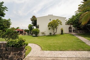 Un edifici amb teulada plana, envoltat d'un jardí ben cuidat i diverses plantes.