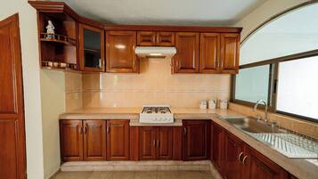 Cocina con gabinetes de madera, estufa a gas, pileta y ventana.