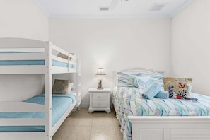A bedroom with bunk beds, a bedside table with a lamp, a bed with a patterned bedspread, and a nightstand. - Relax, Paddle & Unwind in Cape Coral Paradise - Villa Cape Pearl - Roelens (Cape Coral)