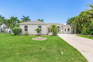 A two-story house with a well-maintained lawn and a driveway leading to the entrance. - Relax, Paddle & Unwind in Cape Coral Paradise - Villa Cape Pearl - Roelens (Cape Coral)