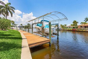A boat docked at a pier with a covered walkway leading to it. - Relax, Paddle & Unwind in Cape Coral Paradise - Villa Cape Pearl - Roelens (Cape Coral)