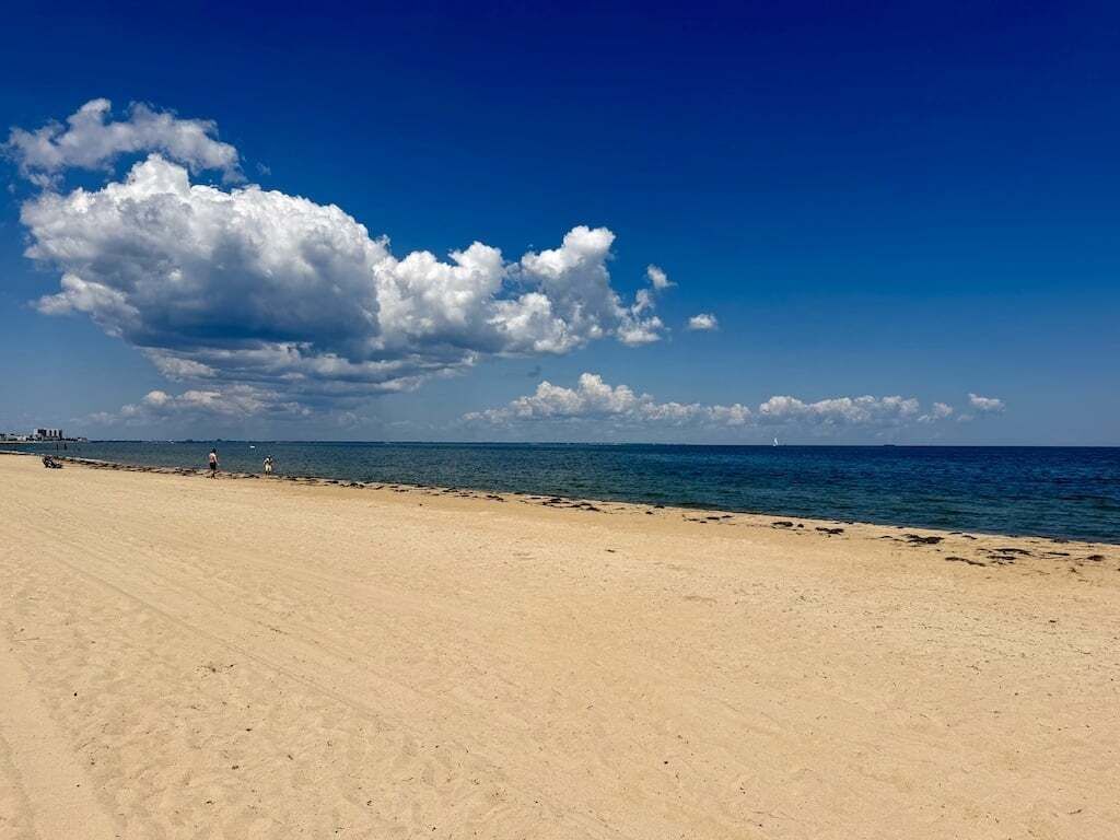 A beach with a clear sky and a large cloud formation.