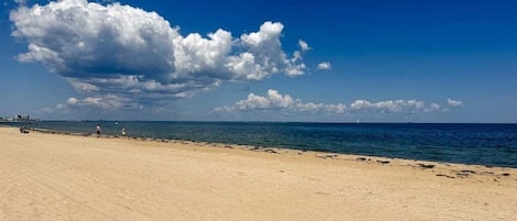 A beach with a clear sky and a large cloud formation.