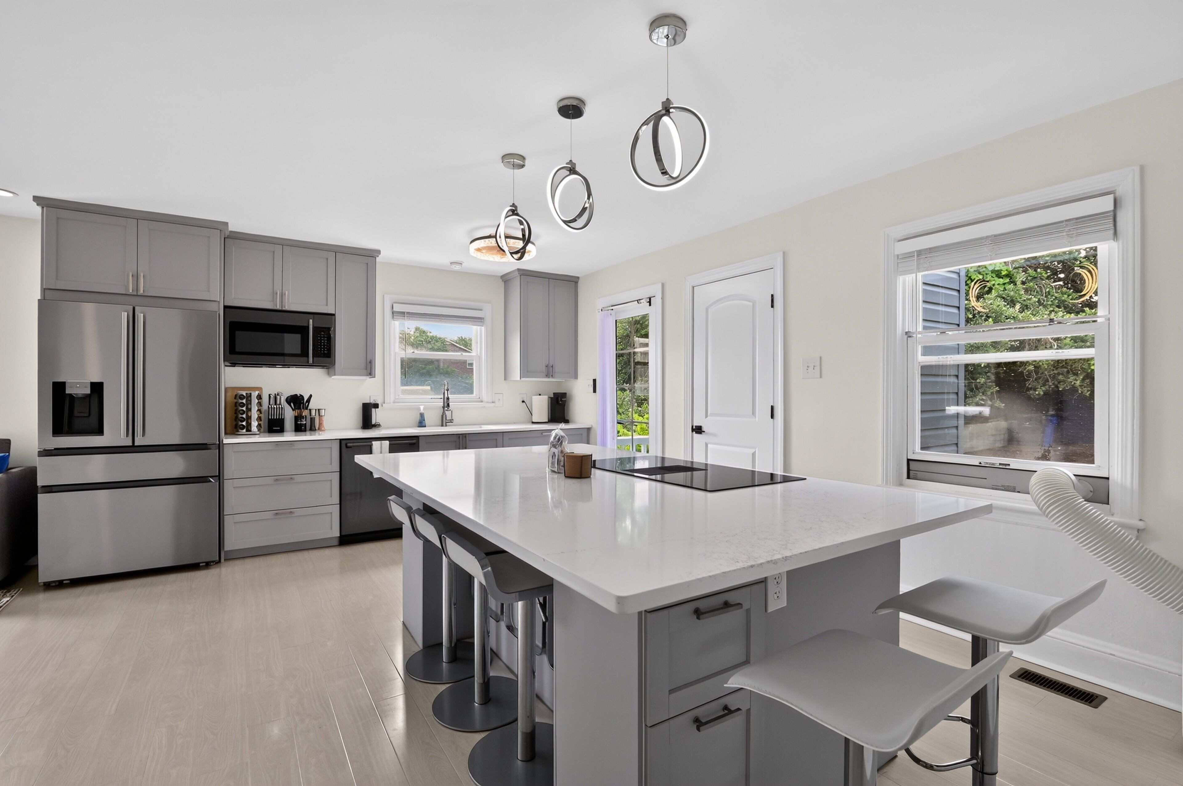 A modern kitchen with stainless steel appliances, a large island, and pendant lighting.