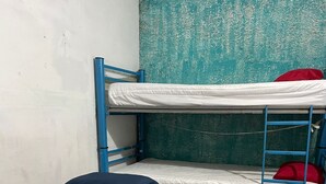 A bunk bed with a blue mattress and a single bed with a blue mattress in a room with a concrete floor and a textured wall. - HOSTAL PUNTACANA (Puerto Vallarta)
