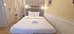 A neatly made bed with a folded towel, a bedside table, and a wardrobe with a mirror. - Apartment - 60 sqm - Montmartre - 6p (Paris)