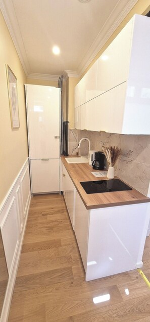 Una cocina moderna con muebles blancos, encimera de madera y estufa integrada.