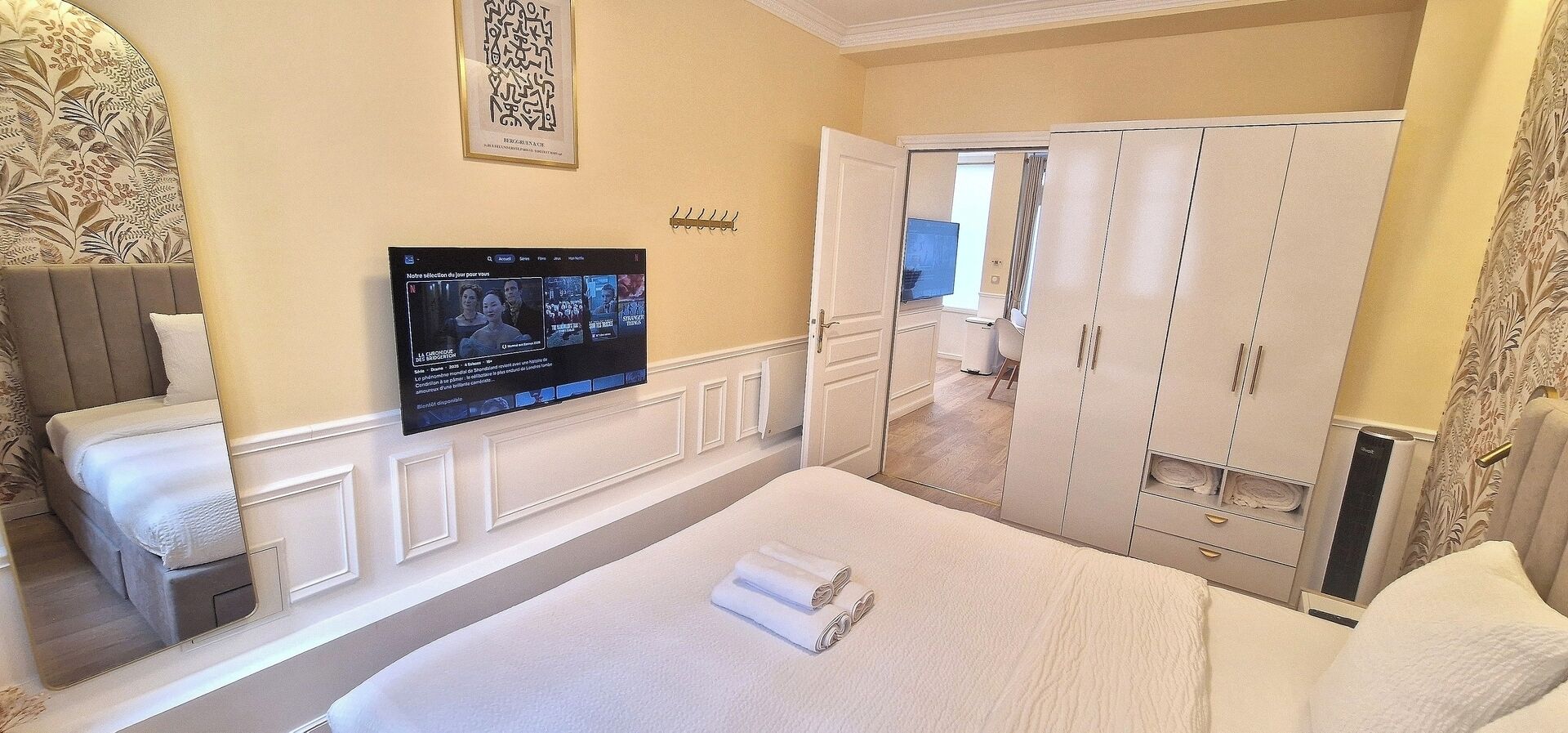 Ein Hotelzimmer mit einem Bett, einem Fernseher, einem Kleiderschrank und einem Spiegel.
