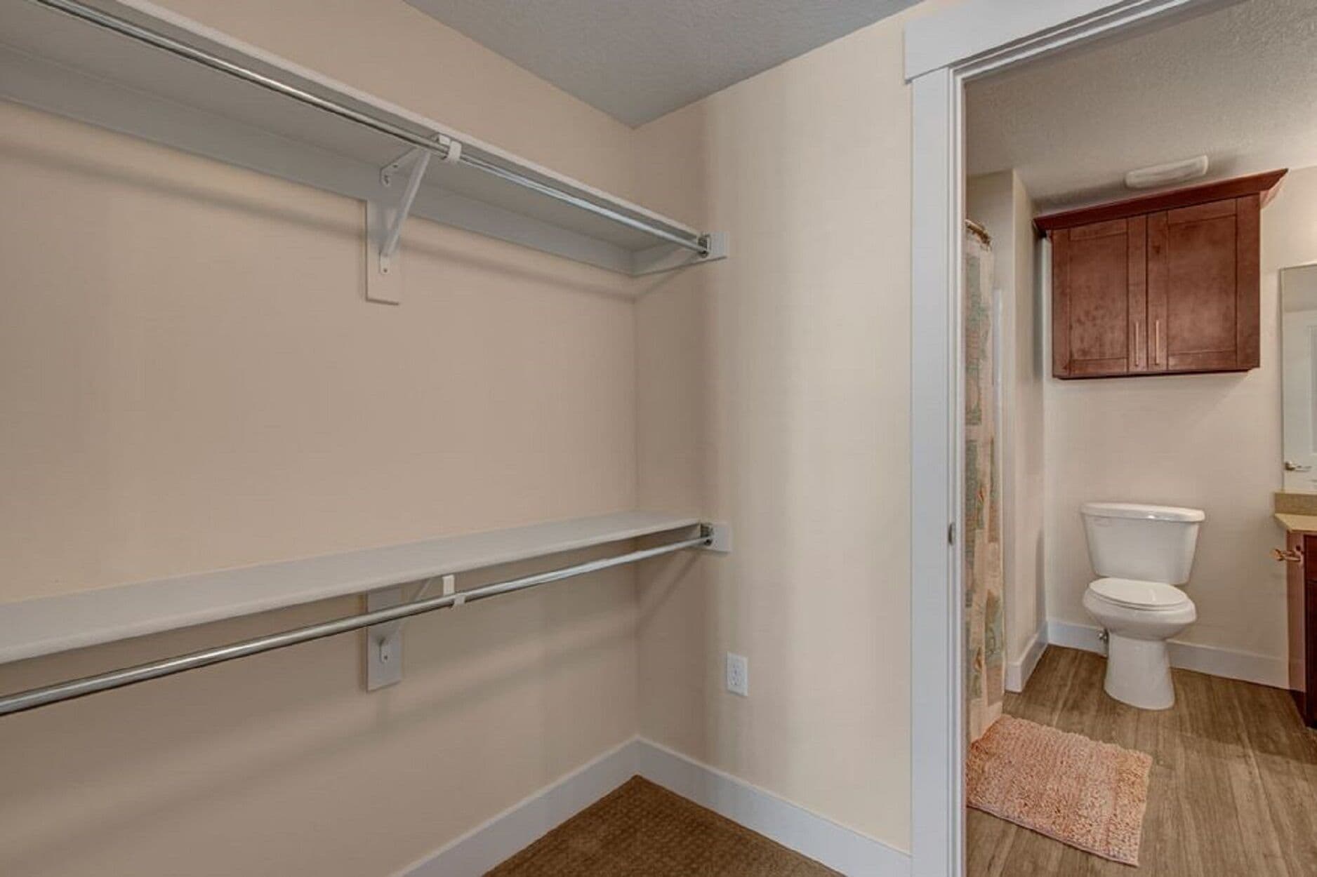A bathroom with a toilet, cabinet, and a shower area with a towel rack.