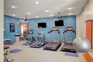 Ein Fitnessstudio mit Laufbändern, Crosstrainern und einem großen Trainingsball.