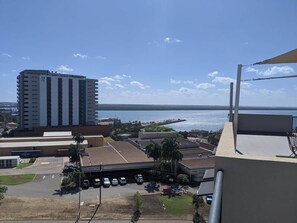 A high-rise building with a view of the ocean and a parking lot with several cars. - City Room Minutes Walk to Waterfront & CDU Campus (Darwin City)