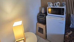 Un ambiente compatto con forno a microonde, un piccolo tavolo con lampada e un divano.