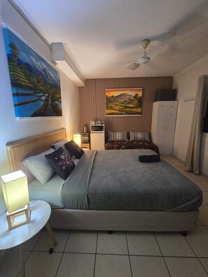 A hotel room with a bed, bedside table, lamp, paintings, and a wardrobe. - City Room Minutes Walk to Waterfront & CDU Campus (Darwin City)