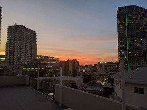 A cityscape at dusk with high-rise buildings, a clear sky, and a balcony overlooking the view. - City Room Minutes Walk to Waterfront & CDU Campus (Darwin City)
