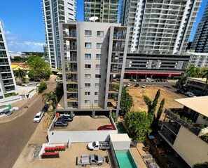 A multi-story residential building with balconies, a parking area, and a swimming pool. - City Room Minutes Walk to Waterfront & CDU Campus (Darwin City)