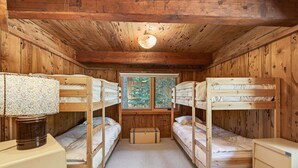 A cabin with bunk beds, a desk, and a window with a view of trees. - Marigold Cabin by Tahoe Getaways - 3BR in Alpine Meadows w/ Ski Shuttle! (Alpine Meadows)