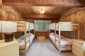 A cabin with bunk beds, a desk, and a window with a view of trees. - Marigold Cabin by Tahoe Getaways - 3BR in Alpine Meadows w/ Ski Shuttle! (Alpine Meadows)