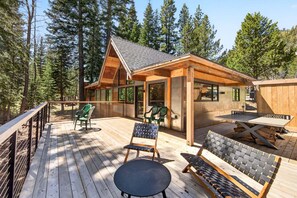 A wooden deck with outdoor furniture, a covered seating area, and a view of a forested landscape. - Marigold Cabin by Tahoe Getaways - 3BR in Alpine Meadows w/ Ski Shuttle! (Alpine Meadows)