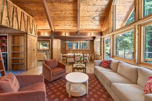 A cozy cabin interior with a dining area, sofa, and a kitchen with a window. - Marigold Cabin by Tahoe Getaways - 3BR in Alpine Meadows w/ Ski Shuttle! (Alpine Meadows)