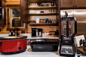 Eine Küche mit einem roten Slow Cooker, einem schwarzen Ninja-Mixer und einer schwarzen Backform.
