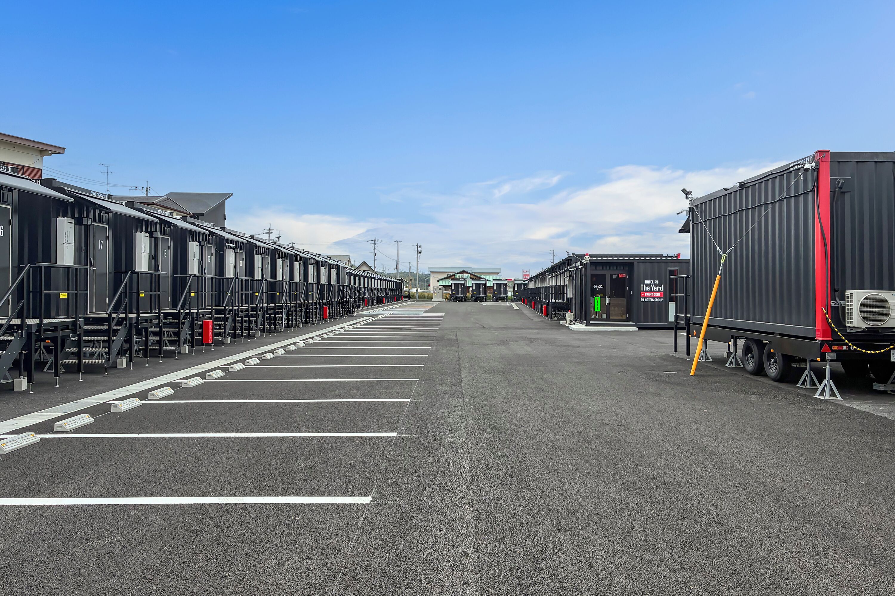 A parking lot with rows of hotel rooms and a large truck parked on the right.