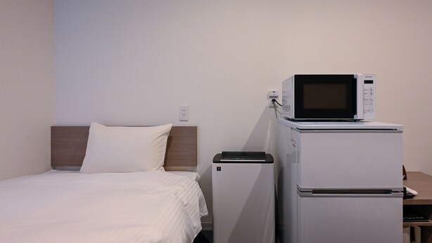A hotel room with a bed, a microwave, and a refrigerator. - HOTEL R9 The Yard Kurate (Kurate)