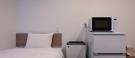 A hotel room with a bed, a microwave, and a refrigerator.