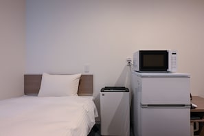 Una habitación de hotel con cama, microondas y refrigerador.