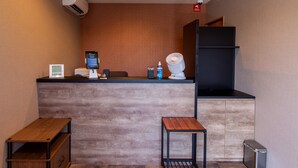 A reception desk with a digital screen, a small table, and a trash bin. - HOTEL R9 The Yard Kurate (Kurate)