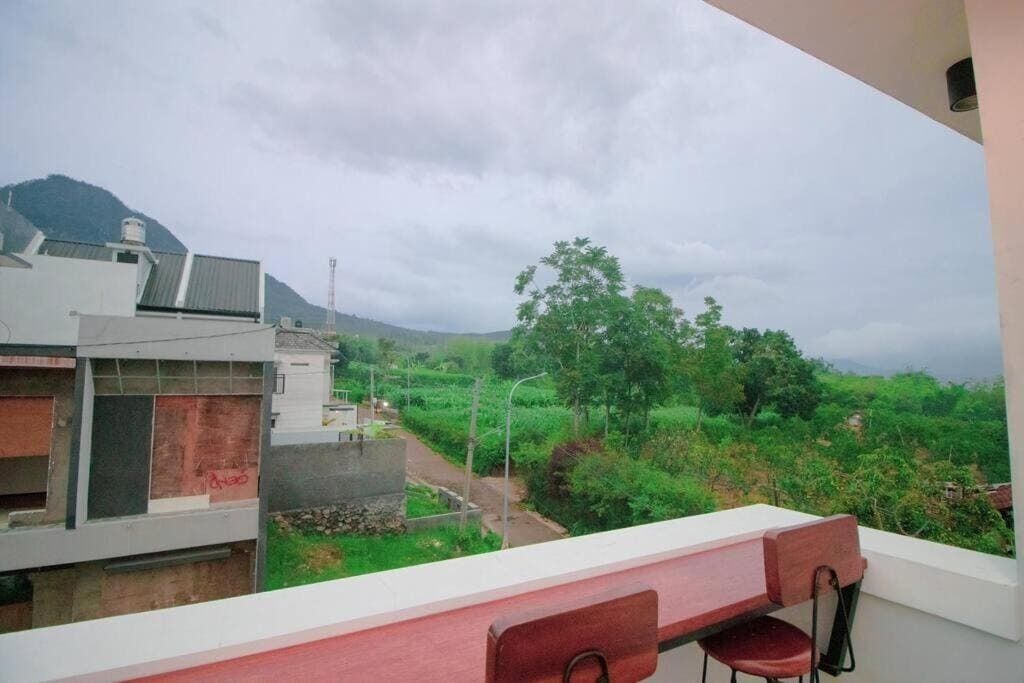 Een balkon met uitzicht op een groen landschap en een berg in de verte.