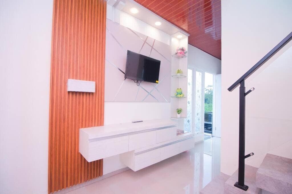 A modern interior with a built-in TV, a white console, and a staircase.
