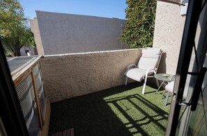 A small outdoor area with artificial grass, a white chair, a small table, and a white wall. - Quiet Mesa Condo with Scenic Golf Course Views & Easy Freeway Access (Mesa)