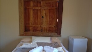 A bed with a quilted mattress, pillows, and rolled towels. - Hospedaria Portal das Montanhas  (Ibicoara)