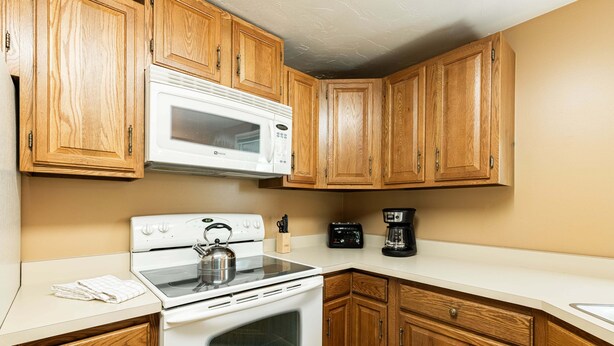 Una cucina con mobili in legno, un piano cottura bianco, un forno a microonde e una macchina per il caffè.
