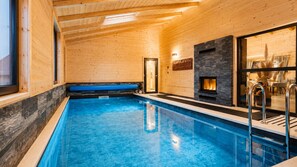 Ein Innenpool mit Holzvertäfelung, einer Sitzbank und einer Steinwand mit Kamin.