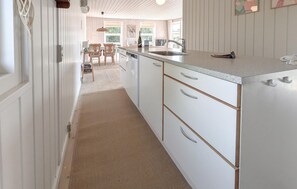 A kitchen with white cabinetry, a countertop, and a sink. There is a dining area with chairs and a table visible in the background. - Awesome home in Nordborg with WiFi (Nordborg)