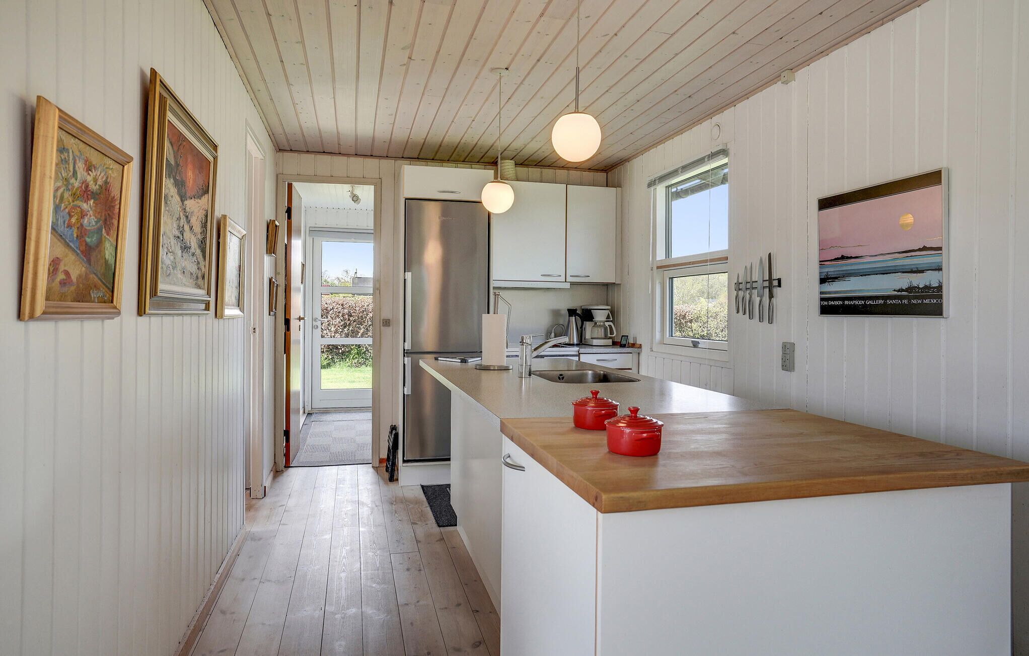 Une cuisine moderne avec un îlot central en bois, des appareils électroménagers en acier inoxydable et une vue sur l’extérieur.