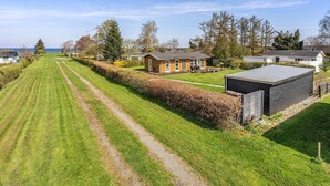Ett bostadsområde med en välskött gräsmatta, ett trähus och ett förråd.