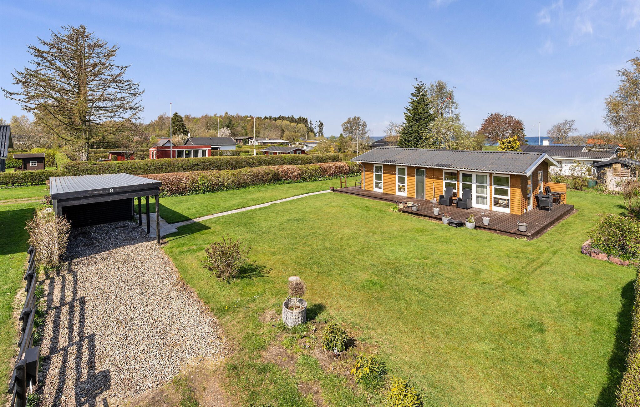 Un bâtiment en bois d’un seul étage, doté d’un espace extérieur couvert avec des sièges et d’une pelouse bien entretenue.